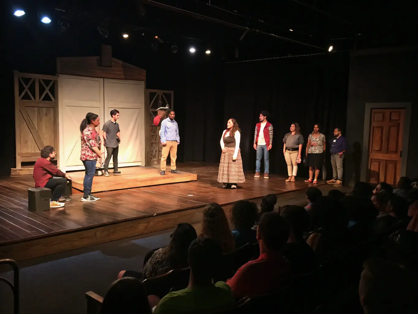 A vibrant image depicting a community theater performance, showcasing actors on stage with enthusiastic audience members in the background, capturing the energy and excitement of live arts.